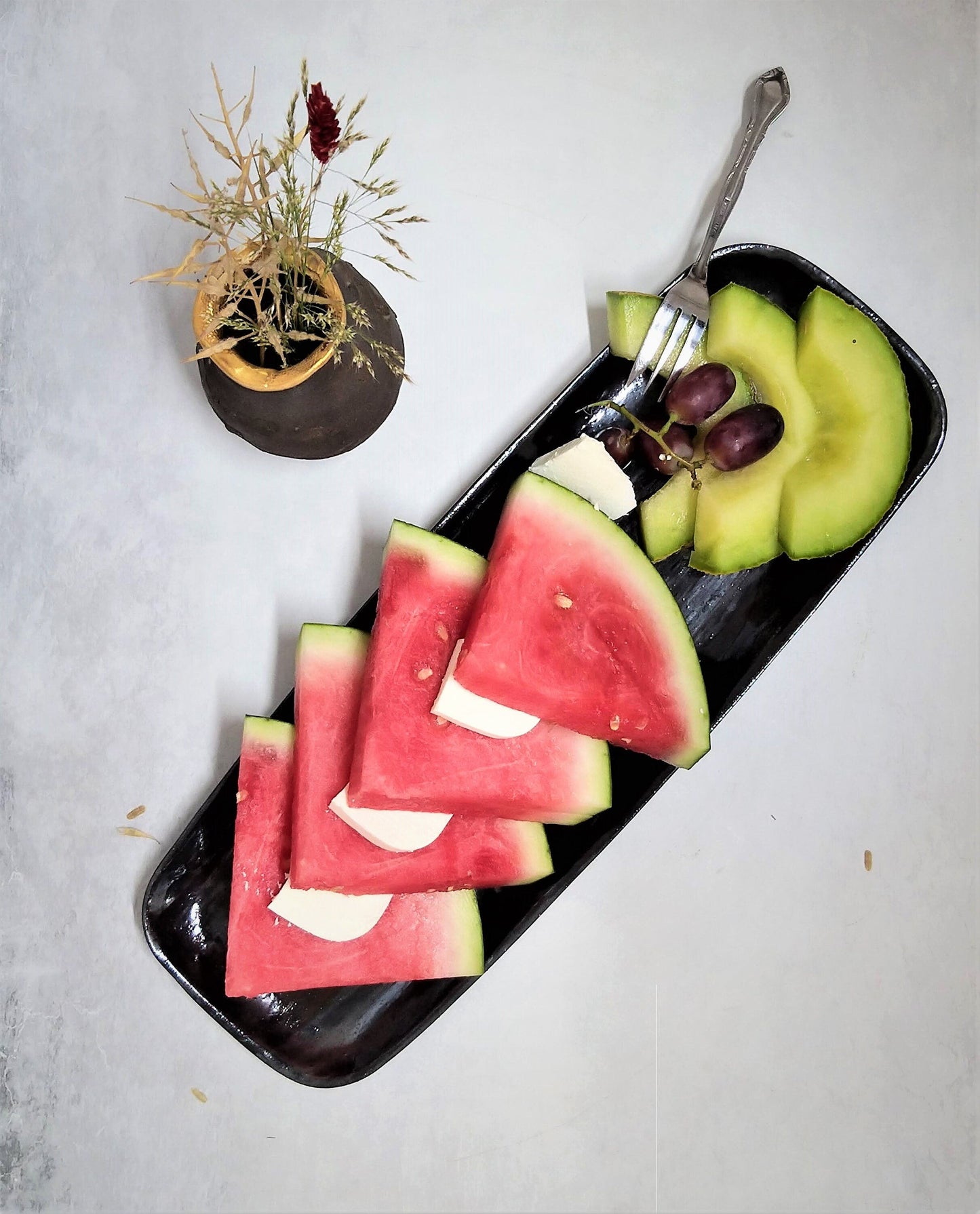 פרוסות אבטיח ומלון עם קוביות גבינה על מגש קרמיקה מלבני